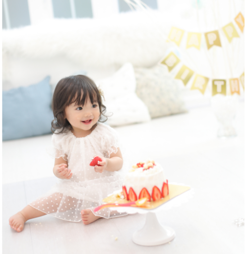 女の子の赤ちゃんがケーキのイチゴを持っている写真